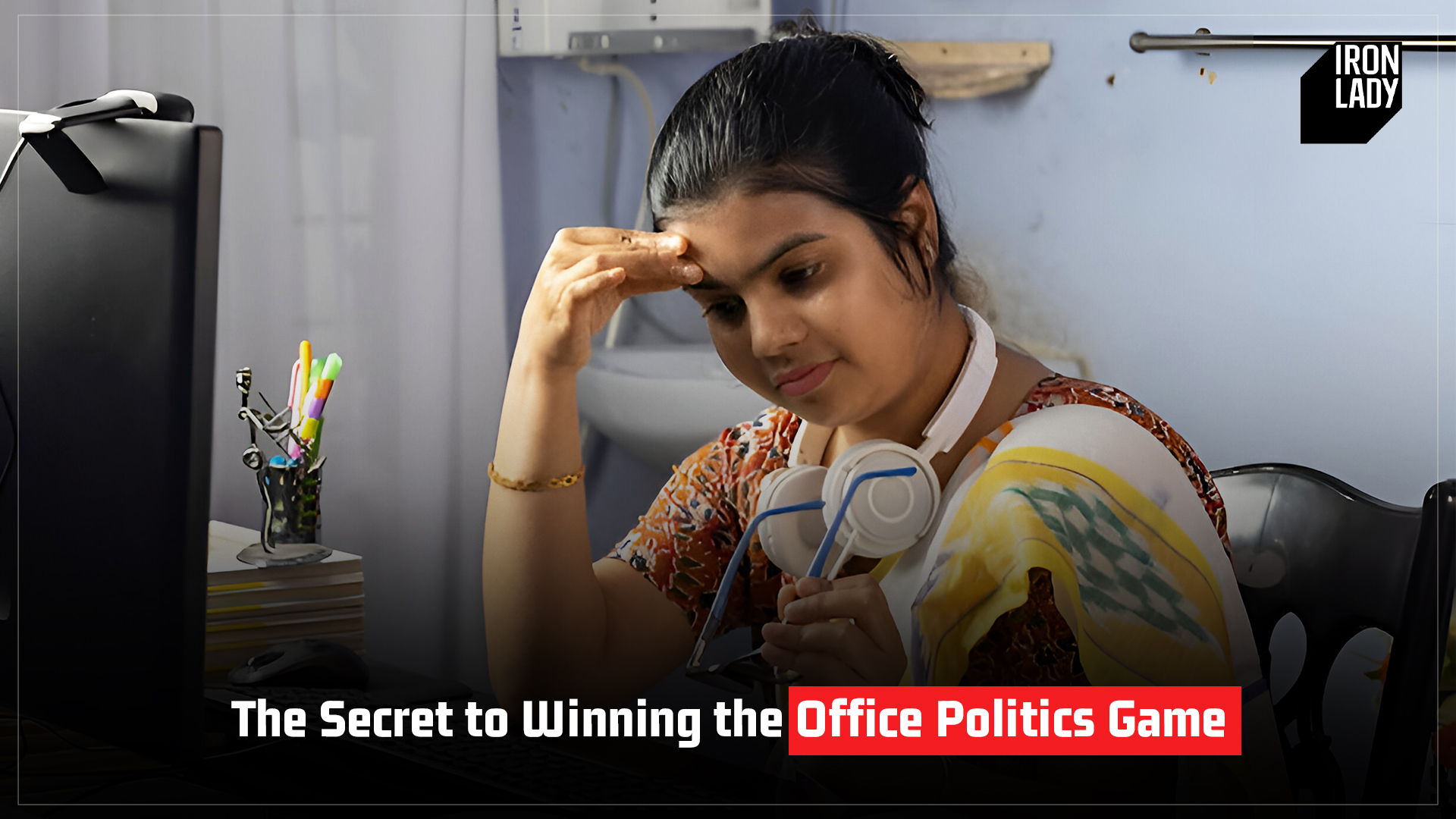 Stressed Indian woman sitting at her desk, learning strategies to win the office politics game, highlighting Iron Lady’s leadership programs.