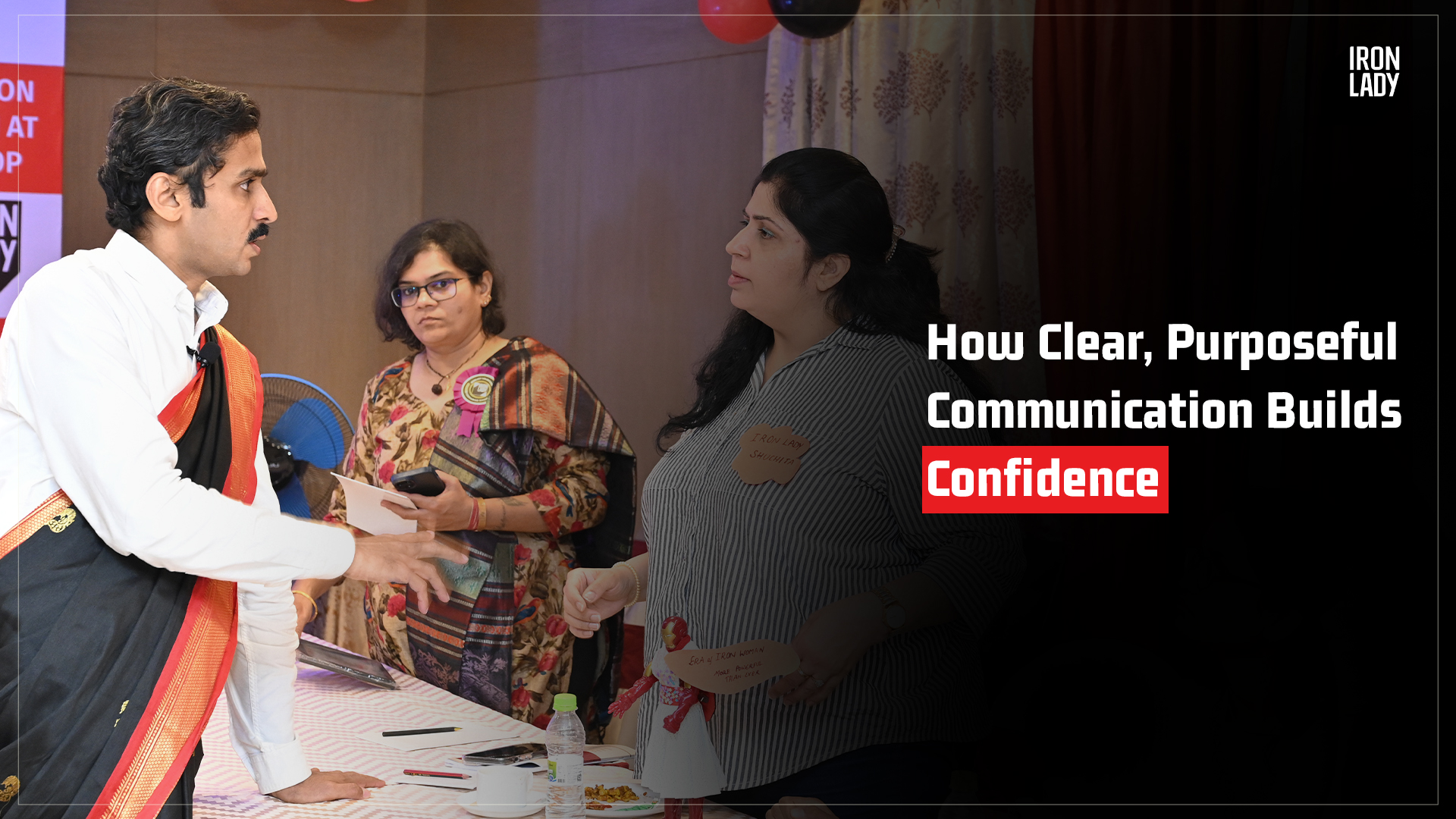 An interactive communication workshop featuring a male facilitator in traditional attire engaging with participants, fostering purposeful communication skills for leadership.