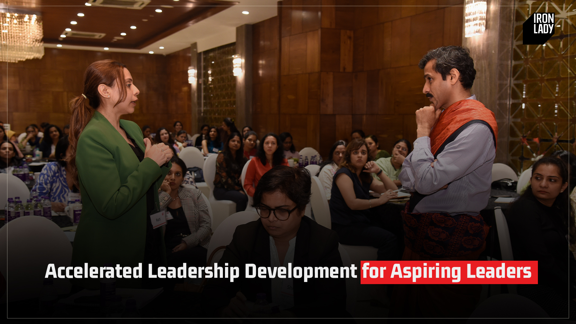 A leadership development workshop in progress, featuring a female speaker addressing a room full of aspiring leaders, with an attentive audience in a professional setting.