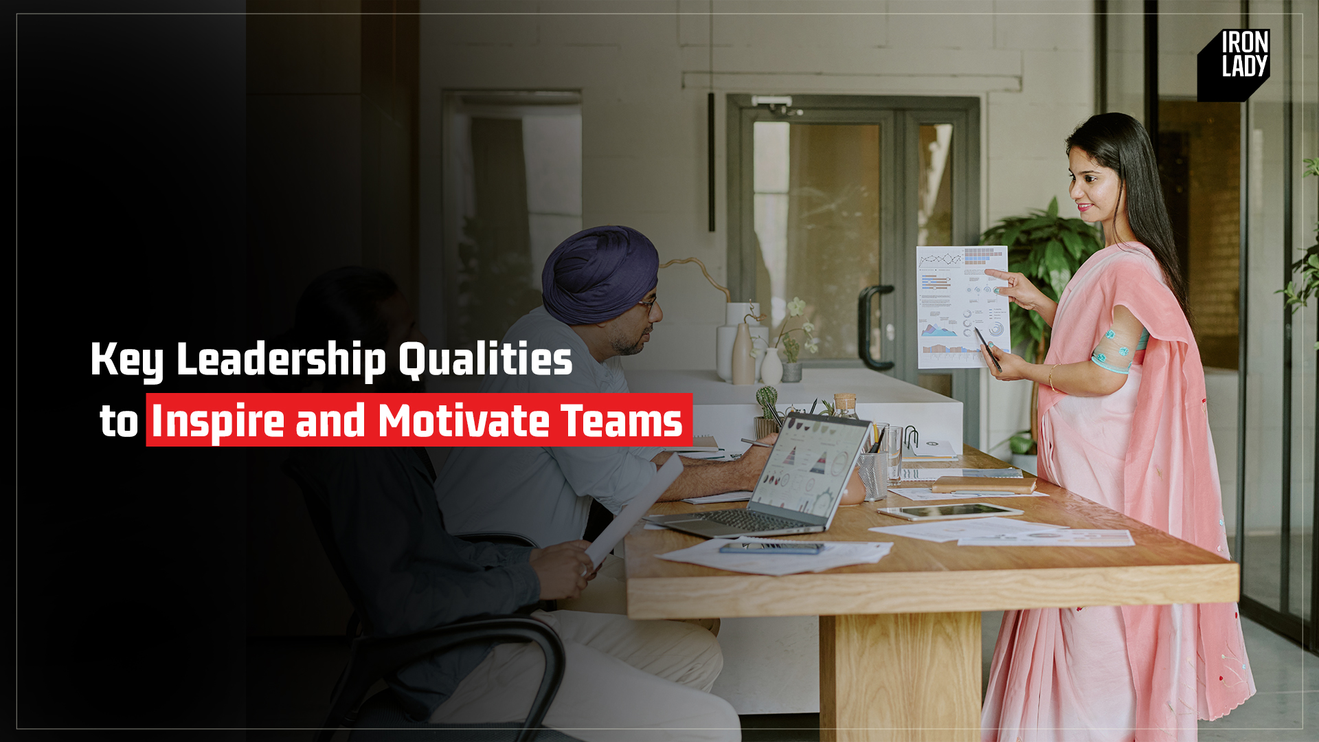 A woman in a pink saree presenting leadership strategies to inspire and motivate teams, engaging with colleagues in a professional setting, with Iron Lady branding in the background.